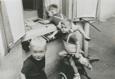 876980 Afbeelding van drie jongetjes die aan het ravotten zijn op de binnenplaats van het opvanghuis 'Meisjesstad' ...